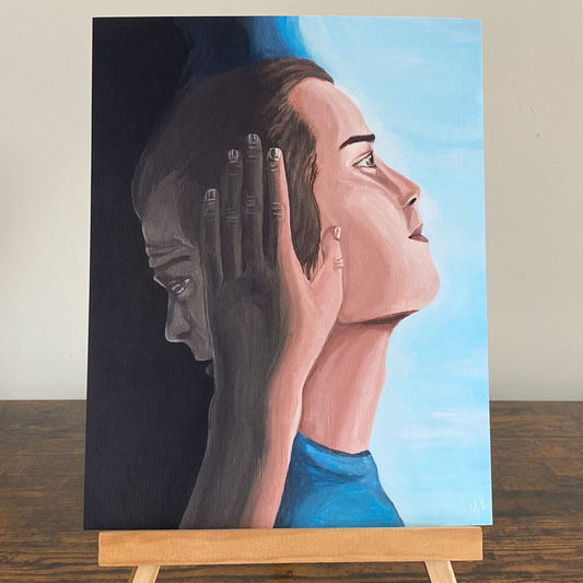A painting displayed on a wooden easel. The artwork portrays a split-image of a person, with one side showing a realistic, confident expression gazing upward against a bright blue background, while the other side is shadowed, depicting a sorrowful, downcast face in grayscale. A hand, transitioning from dark to light, presses against the person's face as if peeling away the sadness. The painting conveys a powerful message of hope and transformation. Surrealism Wall Art, giclée print. Flutter To Bloom