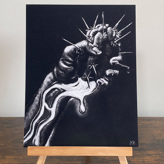 A monochromatic artwork displayed on a wooden easel. The artwork features a highly detailed black-and-white illustration of a clenched hand, pierced by multiple sharp thorns. A white liquid-like substance appears to be dripping from the wounds and flowing down the arm. The dark background contrasts with the stark white highlights, creating a dramatic effect. The artist's initials, "YB," are visible in the bottom right corner. giclée wall art print, NZ Art Print, NZ artwork prints. Flutter to Bloom