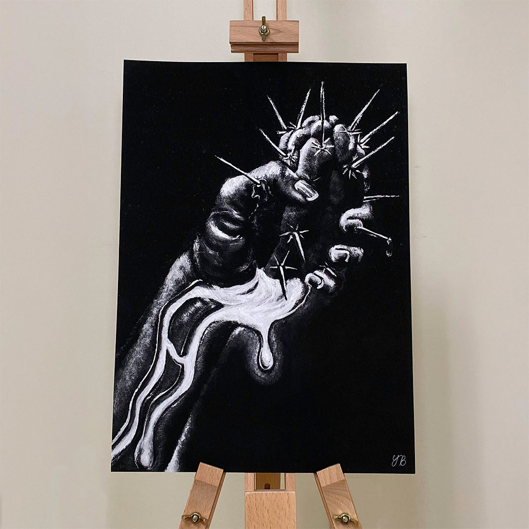 An A3 monochromatic artwork displayed on a wooden easel. The artwork features a highly detailed black-and-white illustration of a clenched hand, pierced by multiple sharp thorns. A white liquid-like substance appears to be dripping from the wounds and flowing down the arm. The dark background contrasts with the stark white highlights, creating a dramatic effect. The artist's initials, "YB," are visible in the bottom right corner. giclée wall art print, NZ Art Print, NZ artwork prints. Flutter to Bloom