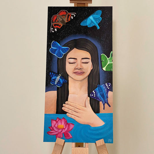 An A3- print of a painting of a serene woman with her eyes closed, her hand resting on her chest as she floats peacefully in water. Above her is a starry night sky. Multiple colourful moths flutter around her head, which she ignores. A pink lotus flower floats on the water near her, further enhancing the calming and meditative mood of the artwork. NZ Artwork Prints, giclée. Flutter To Bloom
