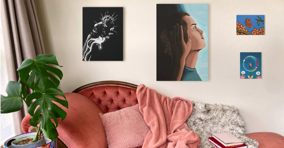  A cosy living room with a pink tufted sofa, pink throw, and Monstera plant. Four artworks hang above: a profile portrait, a black-and-white abstract piece, butterflies with flowers, and a flower bud in a bubble.
